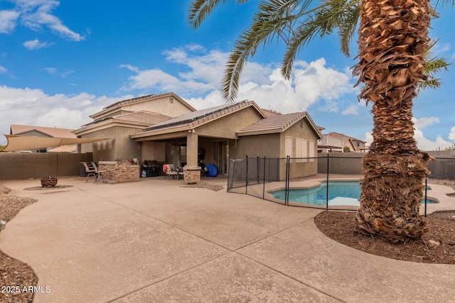 back of house with exterior bar, a fenced in pool, a fire pit, and a patio area