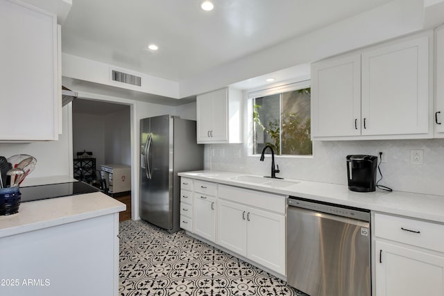 kitchen with stainless steel appliances, white cabinetry, sink, and backsplash