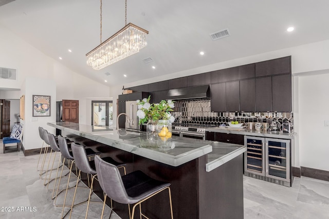 kitchen with wall chimney range hood, a breakfast bar area, a large island, and pendant lighting