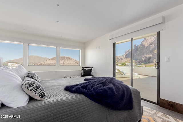 bedroom with multiple windows, a mountain view, carpet floors, and access to outside