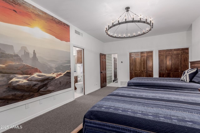 carpeted bedroom featuring multiple closets, ensuite bathroom, and a notable chandelier