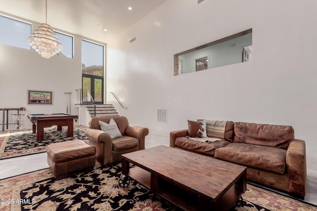 living room with an inviting chandelier, a towering ceiling, and pool table