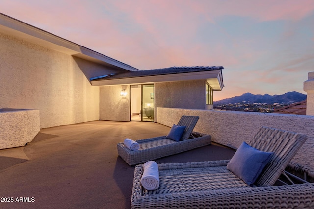 patio terrace at dusk featuring a balcony and a mountain view