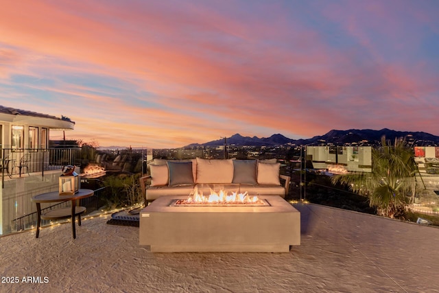 patio terrace at dusk featuring a mountain view and a fire pit