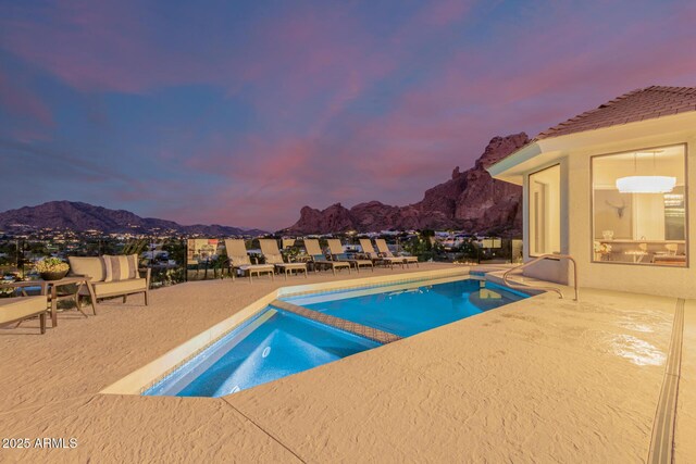 pool at dusk featuring a mountain view and a patio area