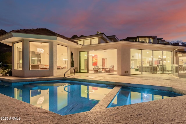 pool at dusk featuring a patio