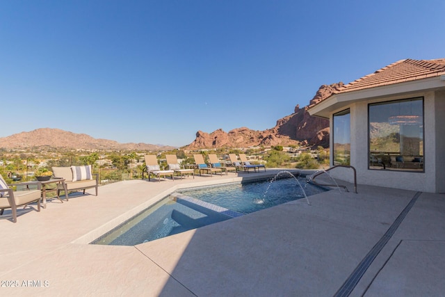 view of pool featuring pool water feature, a mountain view, and a patio