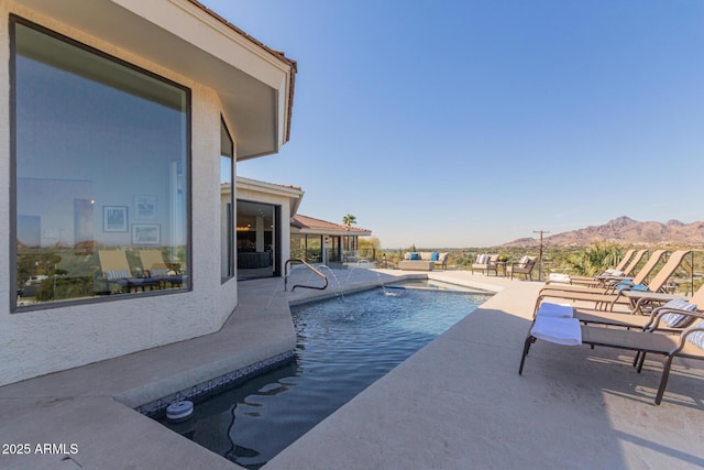 view of swimming pool with a mountain view, pool water feature, and a patio area