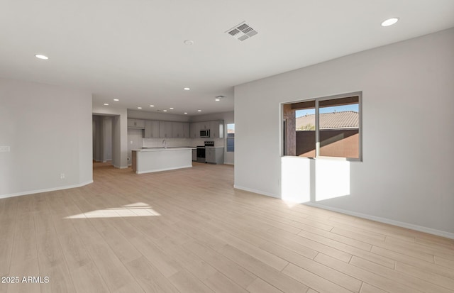 unfurnished living room featuring sink and light hardwood / wood-style flooring