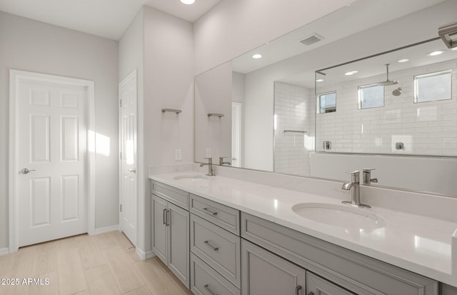 bathroom with a tile shower, vanity, and hardwood / wood-style flooring