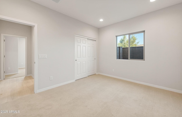 unfurnished bedroom with light colored carpet and a closet