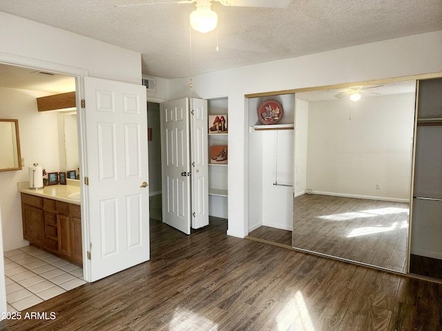 unfurnished bedroom with hardwood / wood-style flooring, a closet, a textured ceiling, and ensuite bathroom