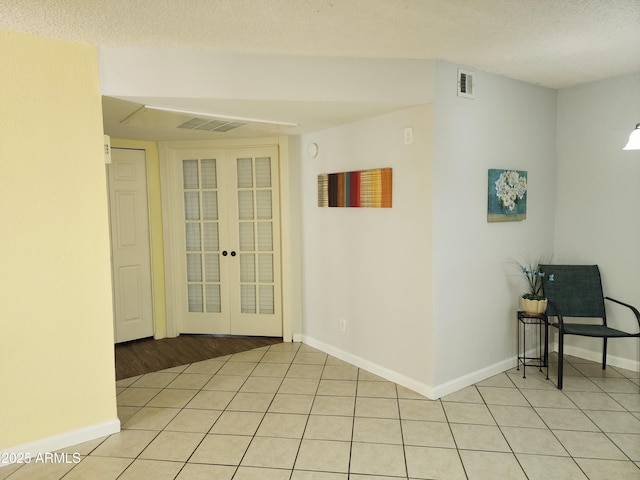 spare room featuring french doors, a textured ceiling, and light tile patterned flooring