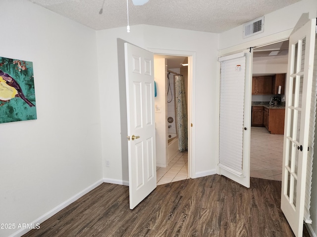 unfurnished bedroom with hardwood / wood-style floors, a textured ceiling, and french doors