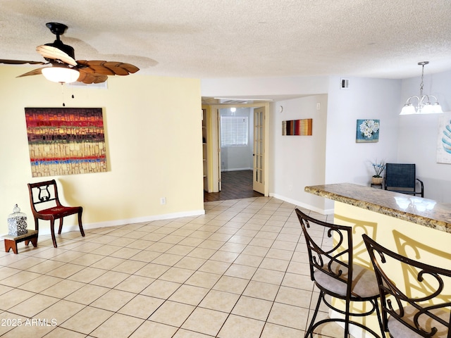 kitchen featuring ceiling fan with notable chandelier, pendant lighting, a textured ceiling, and light tile patterned floors