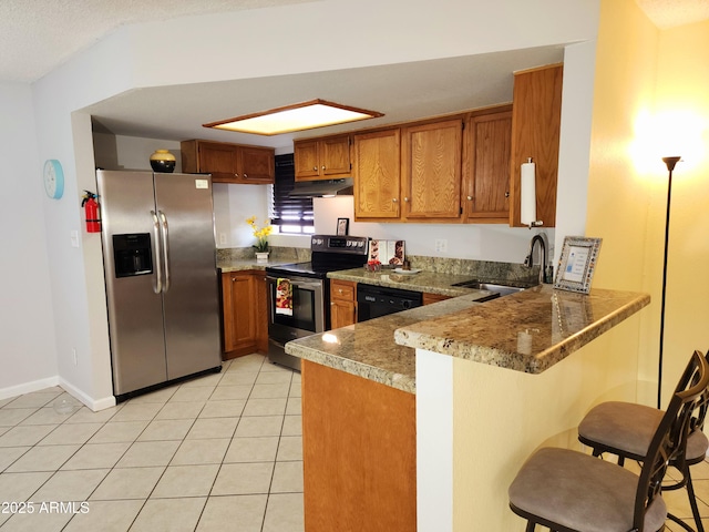 kitchen with appliances with stainless steel finishes, sink, a breakfast bar area, light tile patterned floors, and kitchen peninsula