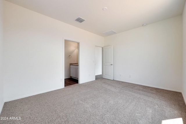 unfurnished bedroom with connected bathroom and carpet floors