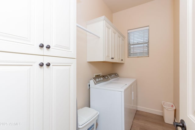 clothes washing area featuring washer and dryer, light hardwood / wood-style floors, and cabinets