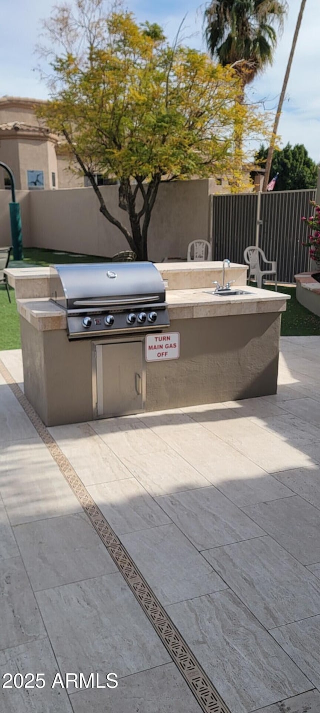 view of patio with exterior kitchen, area for grilling, and sink