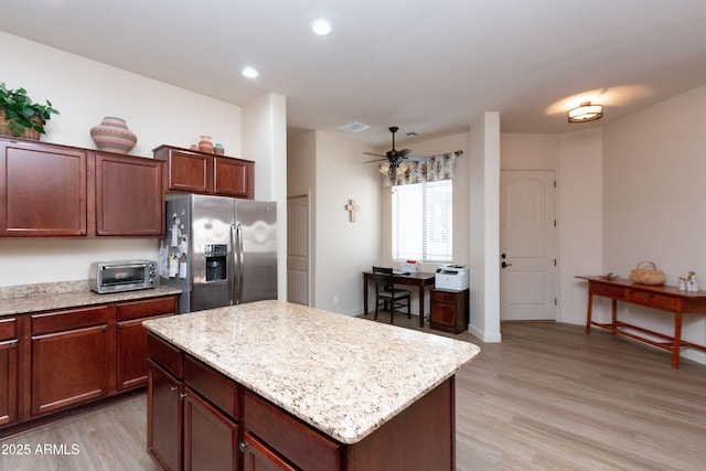 kitchen with stainless steel refrigerator with ice dispenser, light stone countertops, a center island, and light hardwood / wood-style flooring