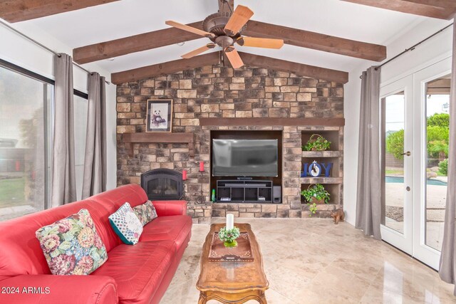 living room featuring ceiling fan, lofted ceiling with beams, a stone fireplace, and tile patterned floors