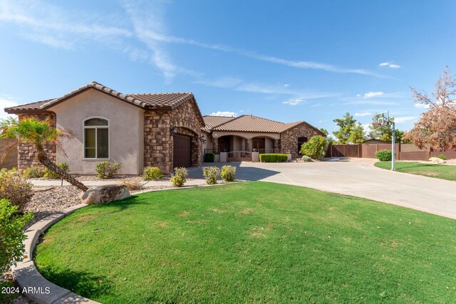 mediterranean / spanish home featuring a garage and a front yard