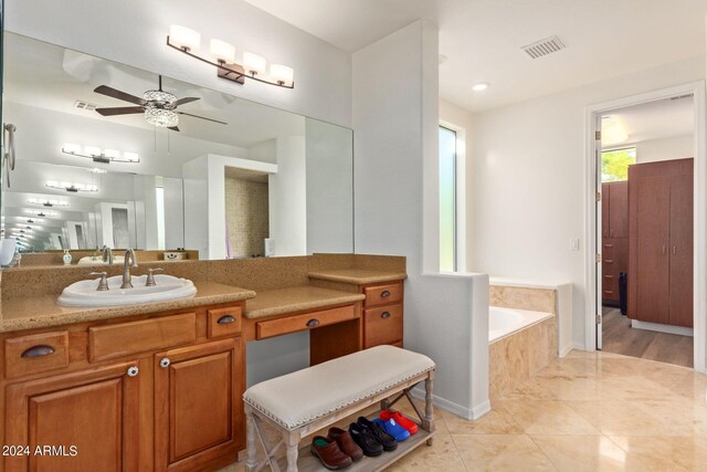 bathroom featuring tile patterned flooring, a relaxing tiled tub, ceiling fan, and vanity