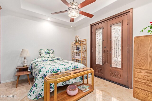 tiled bedroom featuring ceiling fan, french doors, and a tray ceiling