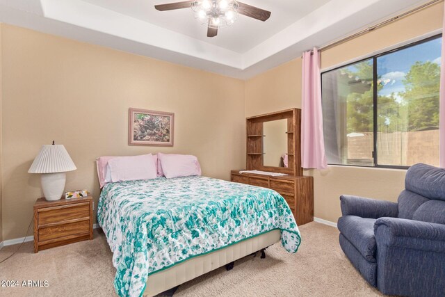 bedroom featuring ceiling fan, light carpet, and a raised ceiling