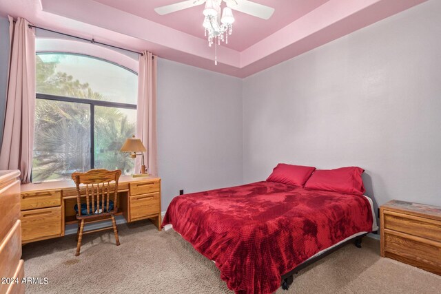 carpeted bedroom featuring ceiling fan and a tray ceiling