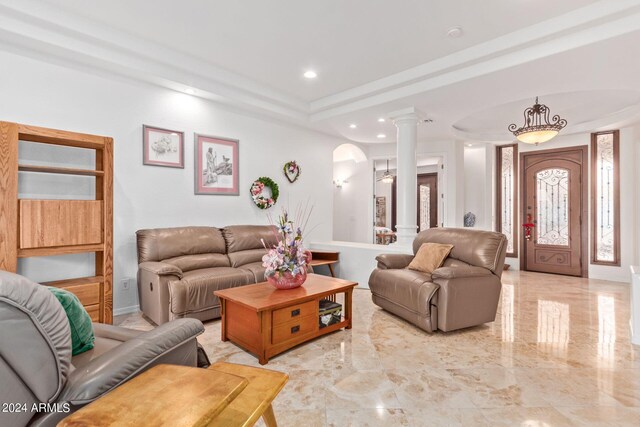 living room with a tray ceiling, ornate columns, and light tile patterned floors