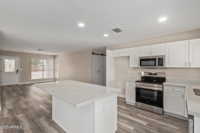 1416 W Highland St, Chandler, AZ 85224 - kitchen with appliances with stainless steel finishes, a barn door, light wood-type flooring, white cabinetry, and recessed lighting