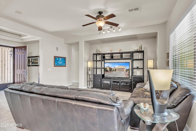 living room featuring tile patterned floors, visible vents, baseboards, and ceiling fan