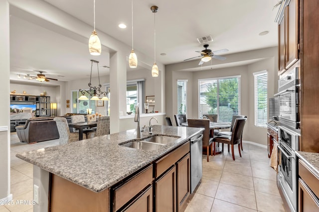 kitchen featuring light stone counters, light tile patterned floors, stainless steel appliances, and a sink