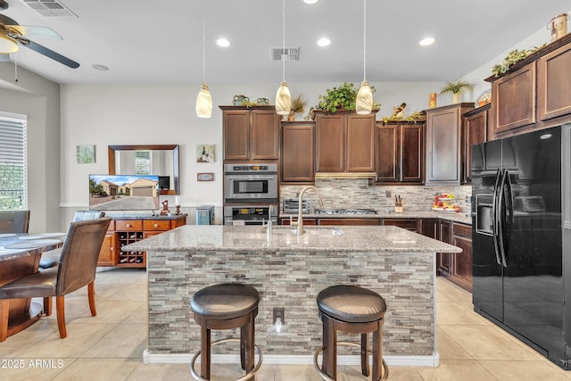 kitchen featuring light tile patterned floors, light stone countertops, visible vents, and stainless steel appliances