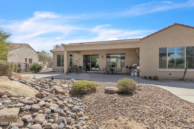 back of property with stucco siding, a patio, and fence