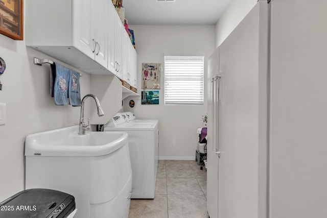 laundry area featuring a sink, cabinet space, separate washer and dryer, light tile patterned floors, and baseboards