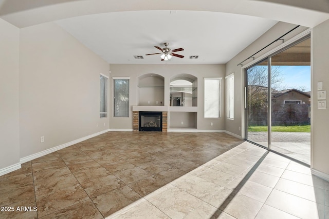 unfurnished living room featuring tile patterned flooring, built in shelves, ceiling fan, and a tiled fireplace