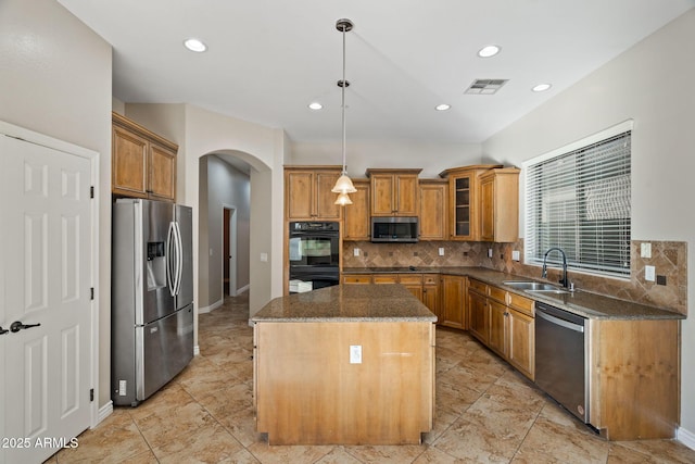 kitchen with backsplash, hanging light fixtures, sink, appliances with stainless steel finishes, and a kitchen island