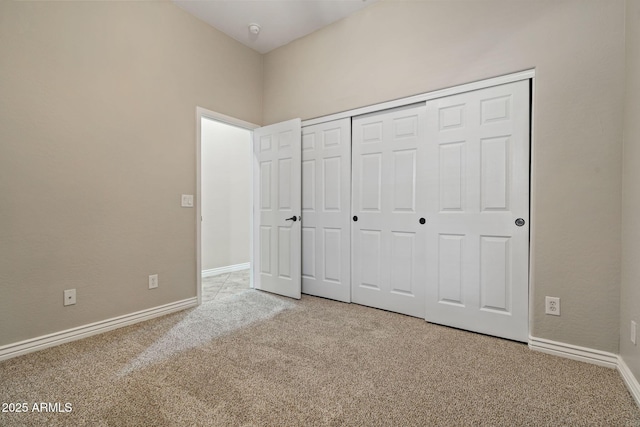 unfurnished bedroom with light colored carpet and a closet