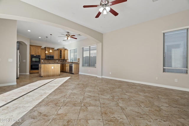 unfurnished living room featuring ceiling fan and sink