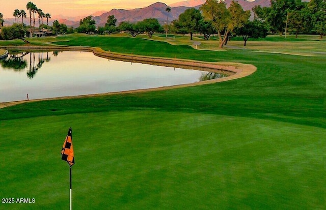 view of community with a water and mountain view, view of golf course, and a yard