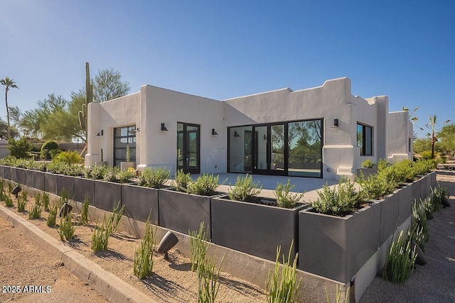 view of front of house with french doors, stucco siding, and fence