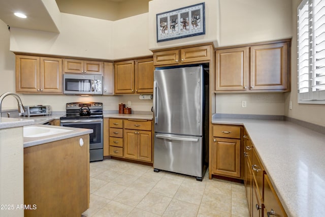 kitchen with stainless steel appliances, light countertops, light tile patterned floors, brown cabinetry, and a high ceiling
