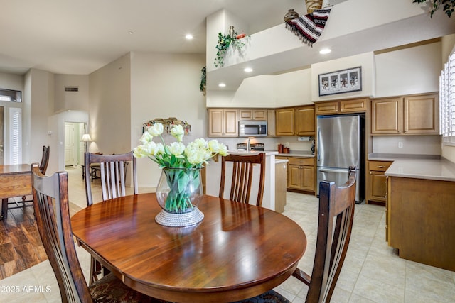 dining area featuring light tile patterned flooring, a high ceiling, recessed lighting, and arched walkways