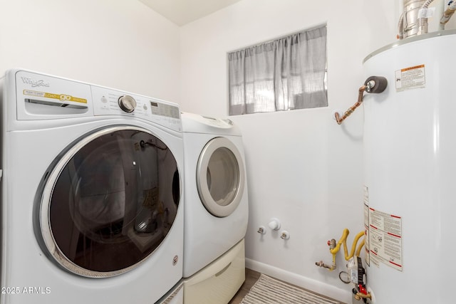 clothes washing area featuring baseboards, washer and dryer, laundry area, and gas water heater