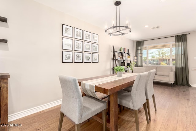 dining area featuring baseboards, a chandelier, and light wood finished floors