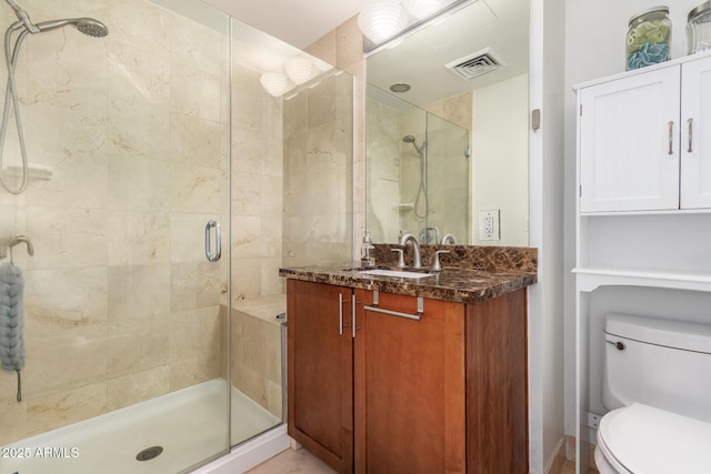 bathroom featuring a shower with shower door, vanity, and toilet