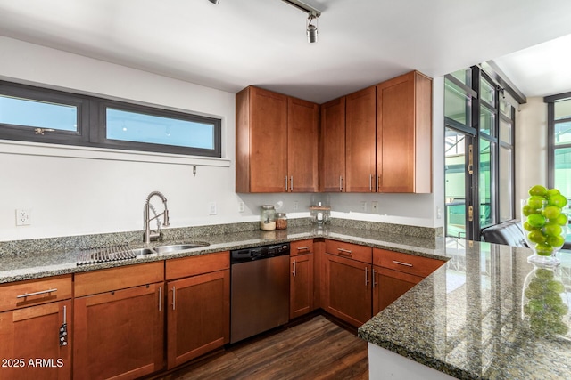 kitchen featuring track lighting, dark stone countertops, sink, dark hardwood / wood-style floors, and stainless steel dishwasher