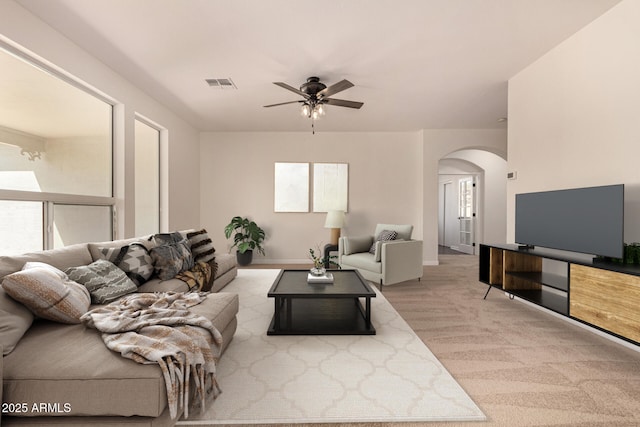 living room featuring arched walkways, ceiling fan, light carpet, visible vents, and baseboards